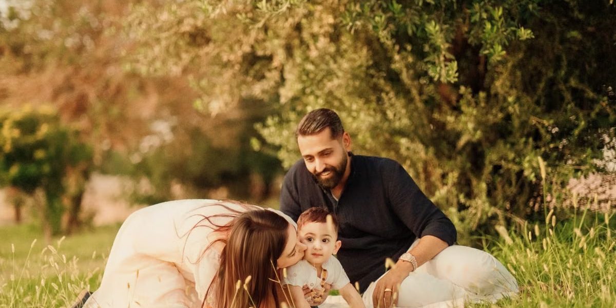 A joyful family with parents and a baby enjoying a sunny day outdoors on a picnic.