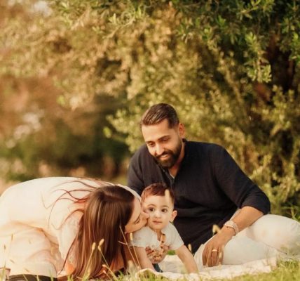 A joyful family with parents and a baby enjoying a sunny day outdoors on a picnic.